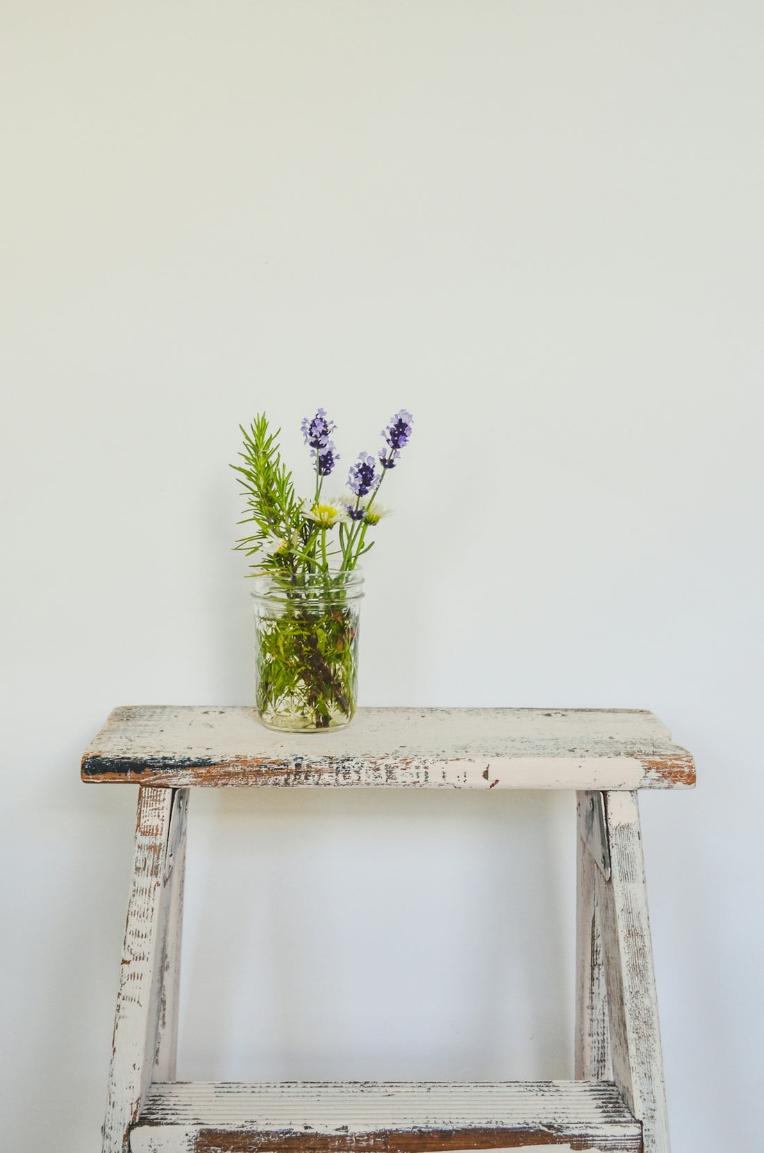 a wooden bench with a vase of flowers on top of it